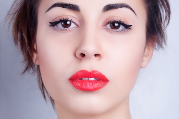 Close-up portrait of brunette woman with red lips and big eyes