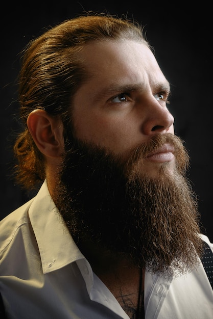 Крупным планом портрет жестокого мужчины с бородой и длинными волосами, он смотрит вверх