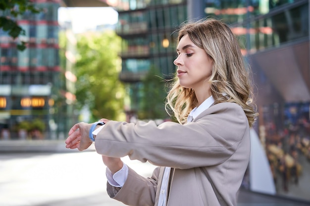 Close up portrait of businesswoman looking at her digital watch\
while waiting for someone outside co