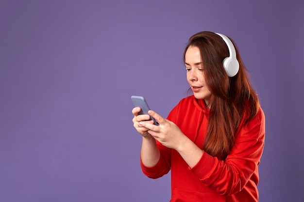 Close up portrait of caucasian woman podcast or music listening on violet background Female listening music in headphones