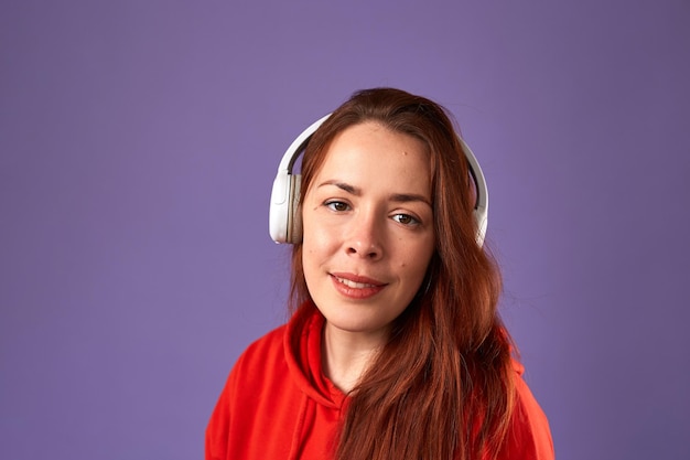 Close up portrait of caucasian woman podcast or music listening on violet background Female listening music in headphones