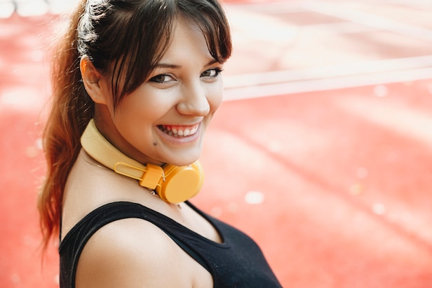 Close up portrait of a charming body positive woman looking at camera laughing while jogging in the morning.