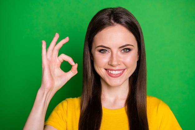 ok-signを示す魅力的な嬉しい陽気なストレートヘアの女の子のクローズアップの肖像画