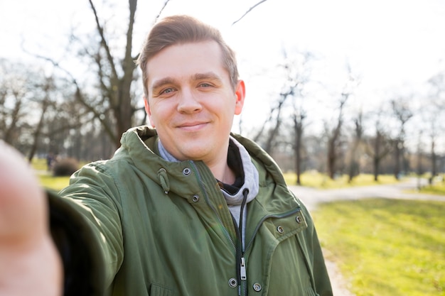 Close up portrait of a cheerful bearded man taking selfie on nature