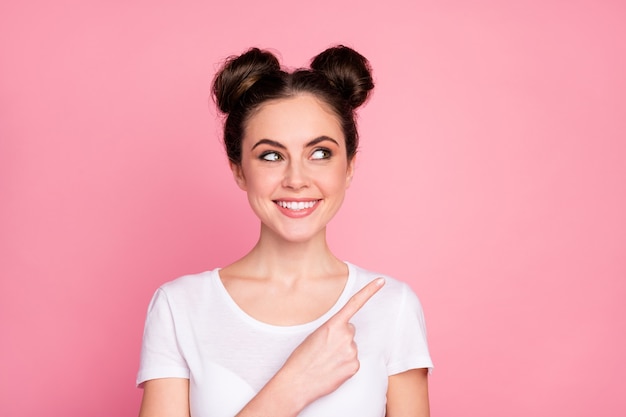 Close-up portrait of  cheerful girl pointing thumb showing ad isolated over pink color background