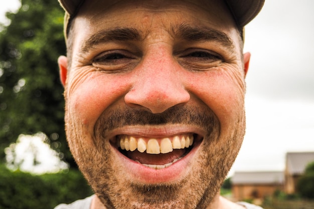 Close-up portrait of cheerful mid adult man against sky