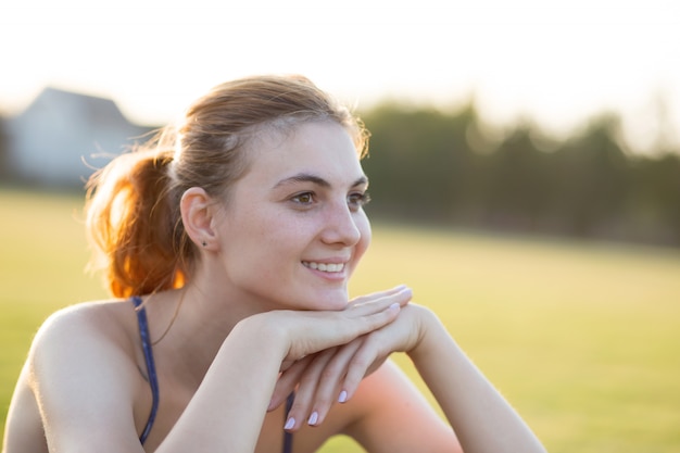 Close up portrait of cheerful smiling young girl with freckles on her face outdoors in sunny summer day. Human expressions and emotions concept.