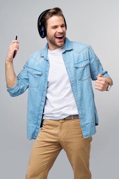 Close up portrait of cheerful young man enjoying listening to music wearing casual jeans outfit