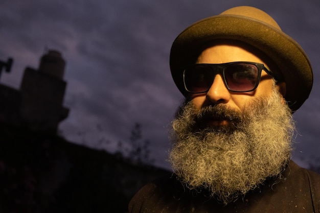 Photo close-up portrait of cool bearded man wearing hat and sunglasses