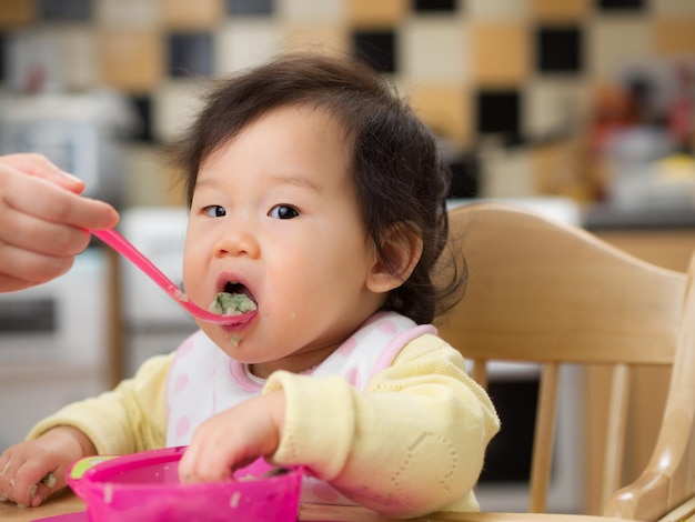 家で食べ物を食べている可愛い赤ちゃんのクローズアップ肖像画