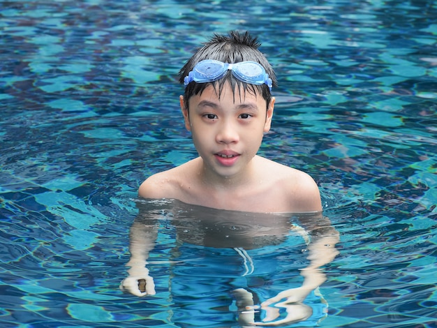 Close-up portrait of cute boy in the swimming pool. 