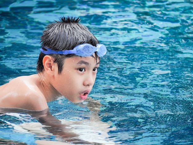 Close-up portrait of cute boy in the swimming pool. 