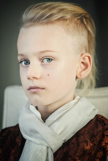 Photo close-up portrait of cute boy wearing scarf sitting at home