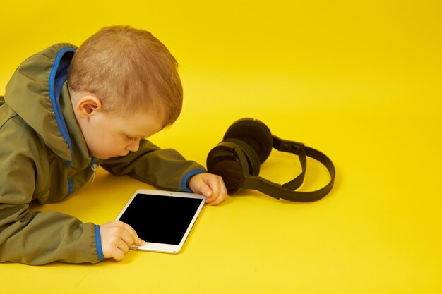 Close-up portrait of a cute boy with headphones, who plays online games, communicates with friends and studies online on a digital tablet.