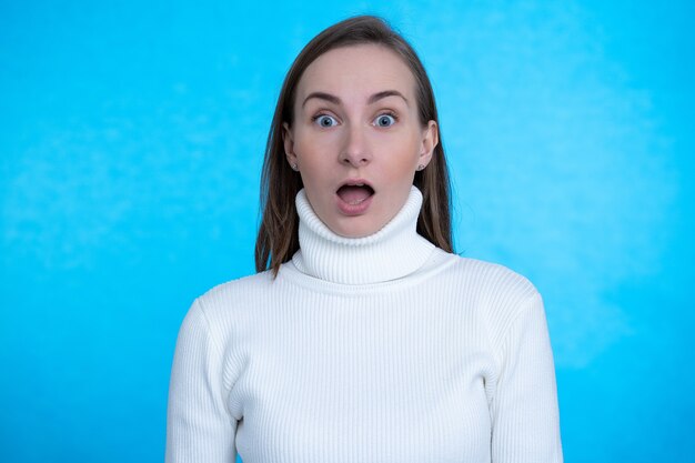 Close up portrait of cute brunette girl, she is shocked, extremely happy, with wide open eyes and mouth