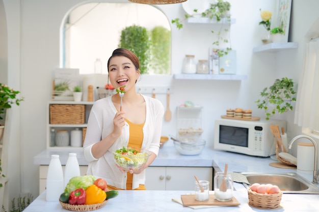 Photo close up portrait of cute girl eating salad on kitchen