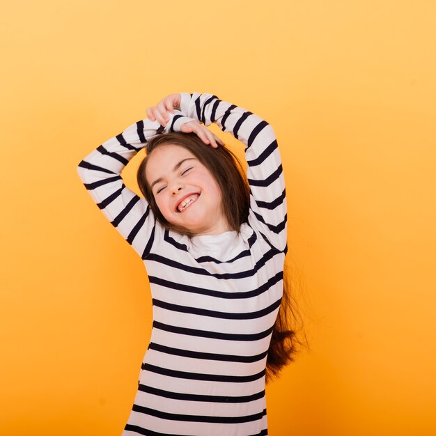 Close-up portrait of a cute little girl. Studio shot over yellow background. Childhood concept.