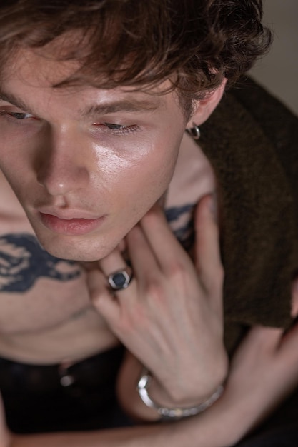 Close up portrait of a cute youngster with tattoos earring and jewelry with bare naked torso