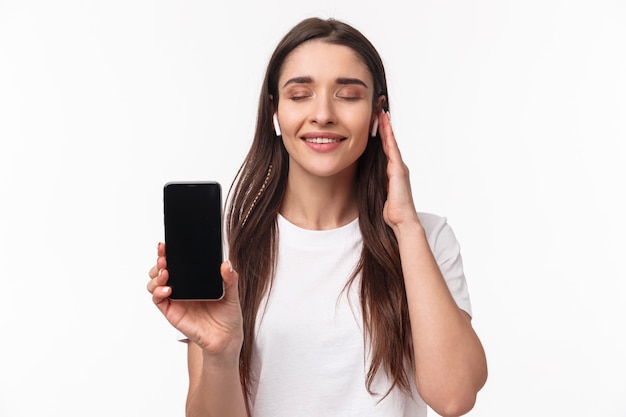 Close-up portrait of delighted, romantic young woman feeling satisfaction of listening favorite playlist