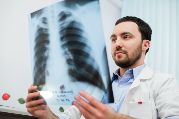 Close up portrait of doctor looking at chest x ray in his office