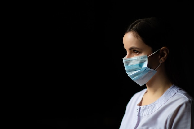 Close up portrait of doctor in medical mask in studio on black background