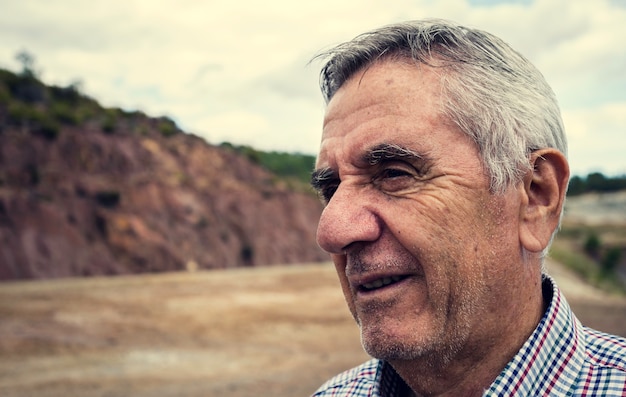 Close-up portrait of an elderly smiling man with white hair and plaid shirt