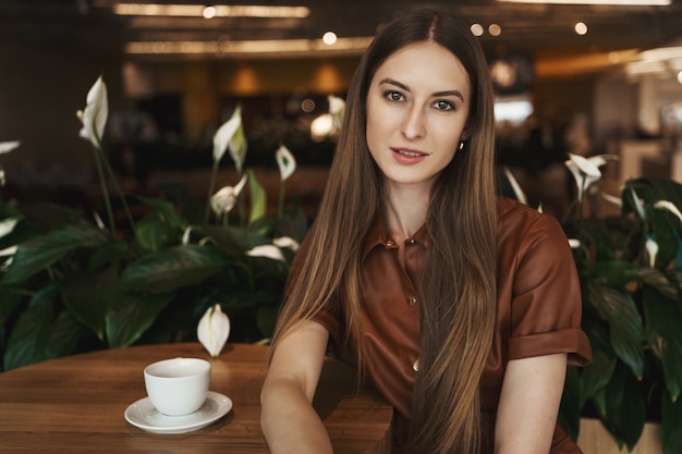 Close-up portrait of elegant charming young woman leaning on a coffee table in a cafe.