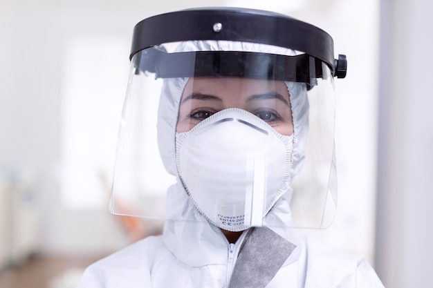 Close up portrait of exhausted doctor with face shield and face mask against fight with coronavirus. Medical personal dressed in protection equipment against infection with covid-19 during global pand