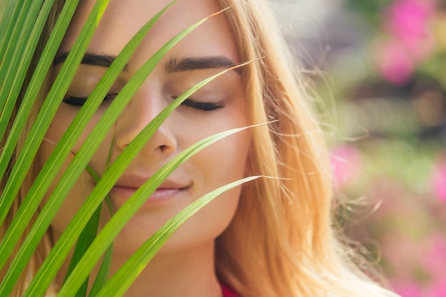 Foto close up ritratto viso donna bionda sopracciglia spesse come cara delevingne con ramo di palma