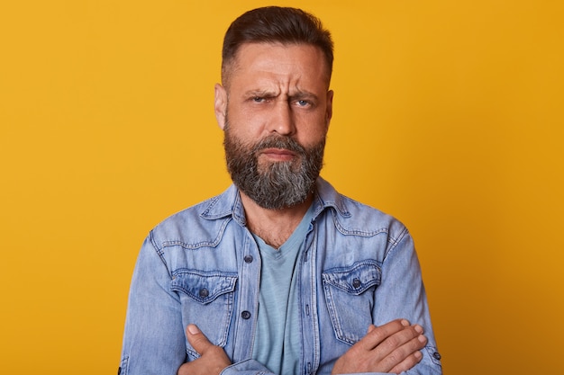 Close up portrait of fashionable middle aged man with beard and trendy haircut wearing denim jacket