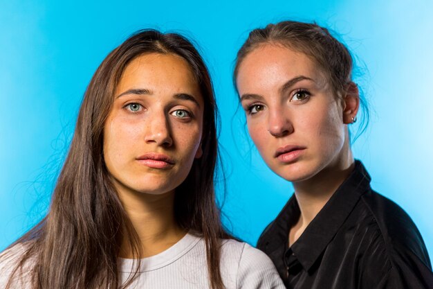 Close-up portrait of female friends standing against blue background