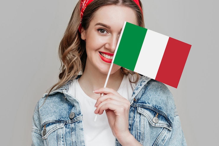 Photo 笑顔で灰色の背景に分離された小さなイタリア国旗を保持している女子学生の肖像画をクローズアップ