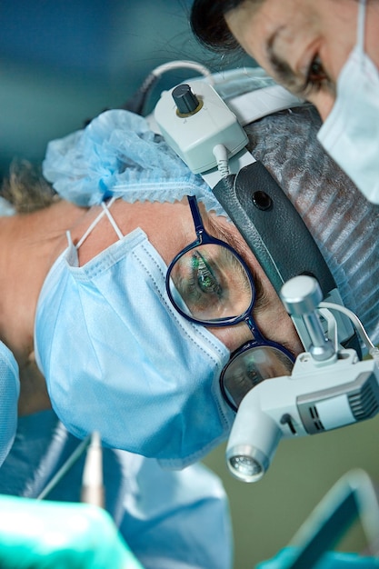 Close up portrait of female surgeon doctor wearing protective mask and hat during the operation Healthcare medical education surgery concept