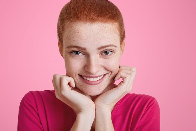 Close up portrait of freckled positive young woman with happy look, broad smile, has ginger hair, being in good mood as going to have date with boyfriend. Cute redhead girl has joyful expression