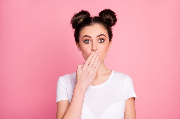 Close-up portrait of funny girl closing mouth with palm
isolated over pink background