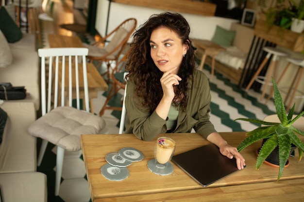 Photo close up portrait funny happy face of young pretty woman with curly hair drinking and enjoying coffe