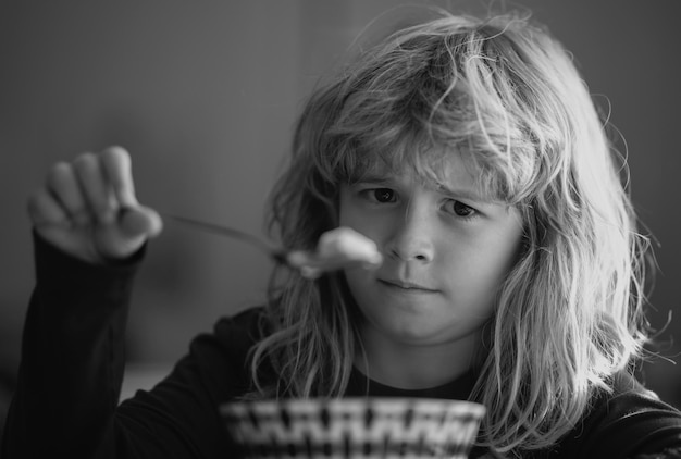 Foto ritratto ravvicinato di un bambino divertente che mangia un ragazzo triste che mangia una sana zuppa di noodle al pollo per pranzo infelice b