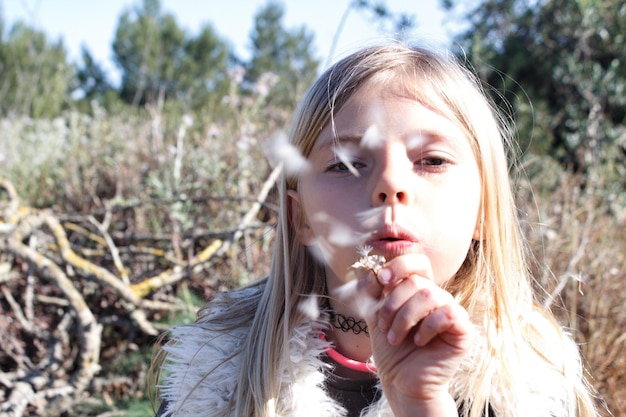 close-up portrait of girl blowing dandelion