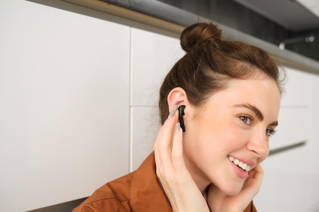 Close up portrait of girl enjoying listening to music in wireless earphones smiling wearing