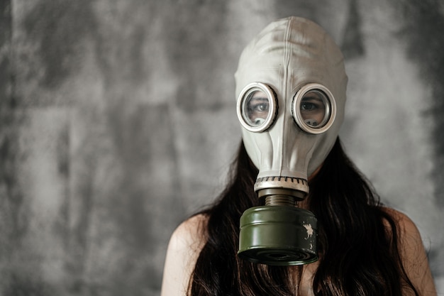 Photo close-up portrait of a girl in a gas mask on a gray background