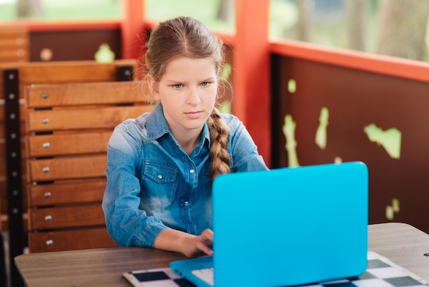 Ritratto ravvicinato di una ragazza dietro un computer portatile, un bambino in età scolare lavora su un computer portatile.