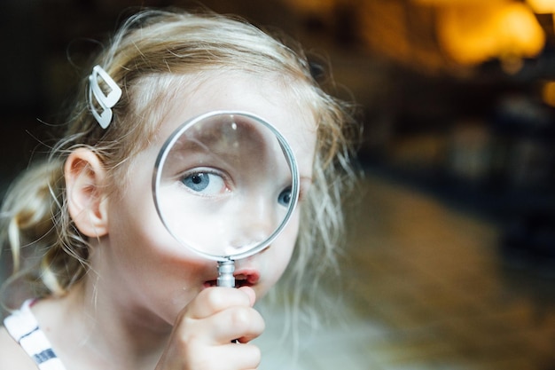 close-up portrait of girl looking through magnifying glass