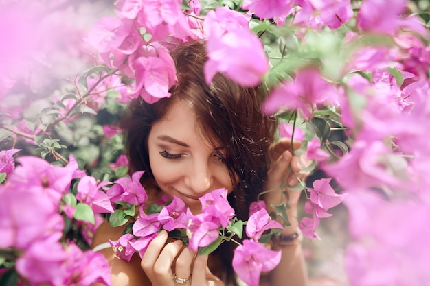 ピンクの花の背景に公園で肖像画の女の子を閉じる