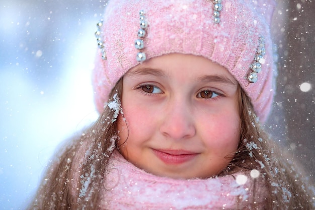 close-up portrait of a girl of primary school age against the backdrop of snowfall