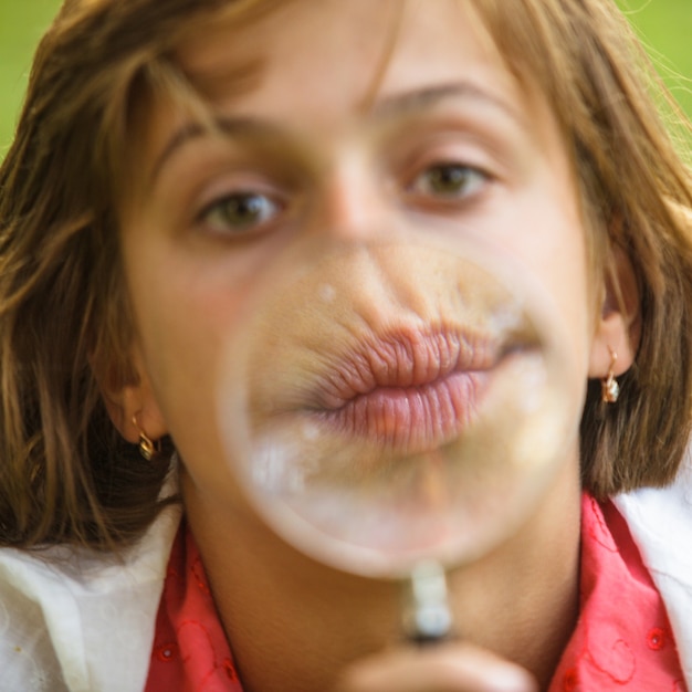 Макро портрет девушки, которая играет с увеличительным стеклом