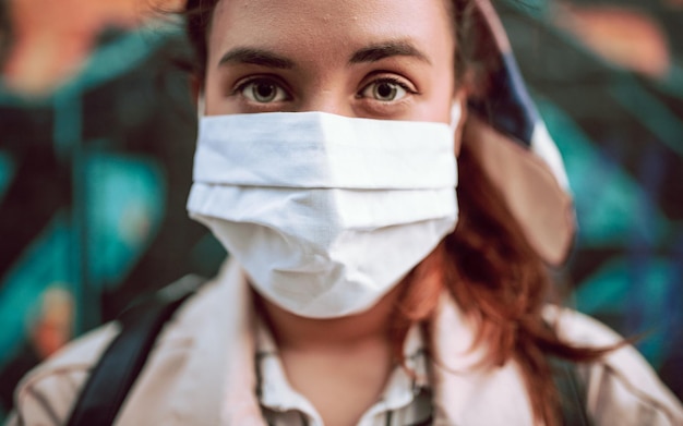 Foto ritratto ravvicinato di una ragazza che indossa una maschera davanti a un muro di graffiti colorato