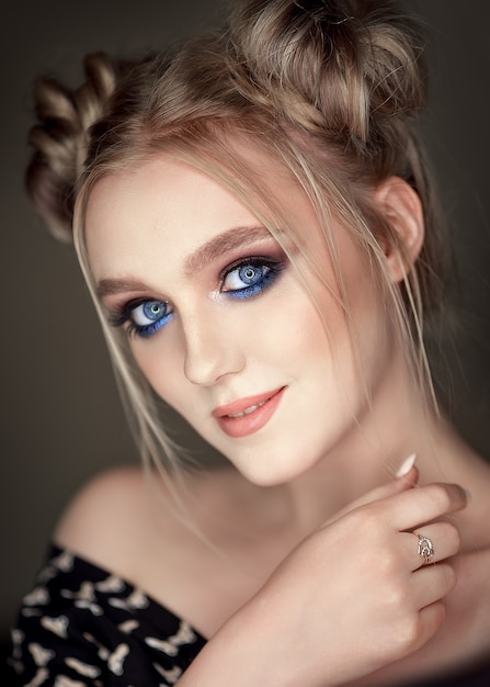 Макро портрет девушки с голубой косметикой с пучками на голове.
