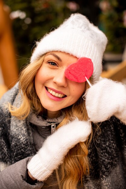 Close up portrait of girl with lollipop in shape of heart.