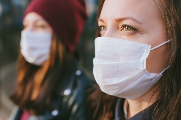 Close-up portrait of a girl with a mask on the background of a woman in the distance.