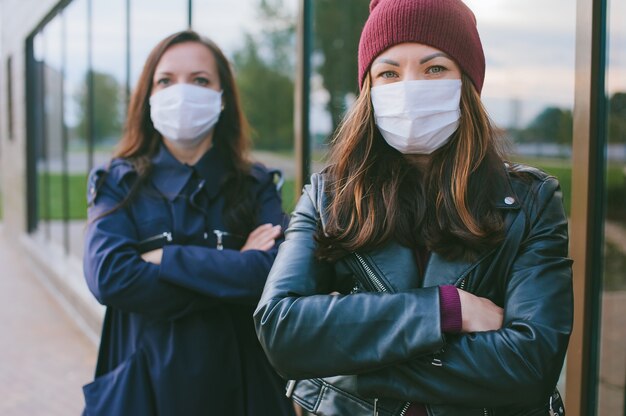 Close-up portrait of a girl with a medical mask on the background of another girl.